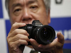 Olympus' president Hiroyuki Sasa poses with his company's new OM-D E-M1 digital camera during its unveiling in Tokyo in this September 2013. | Reuters