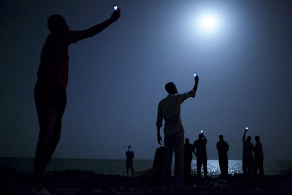John Stanmeyer took this photograph for National Geographic of African migrants near Djibouti city, raising their phones in an attempt to capture an inexpensive signal from neighboring Somalia. It won the World Press Photo of the Year award. | John Stanmeyer / VII for National Geographic