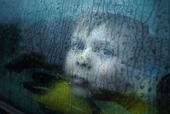I was about to go to a shop with my nephew on a rainy day. I got out of my parked car first and then realized that all the windows had fogged up. I saw a great photo opportunity. Since I had my camera right there, I asked my nephew to stay inside, while I take a couple of photos. He pressed his nose against the window, as he waited and, I had an image out of seemingly nothing. | EyeVoyage