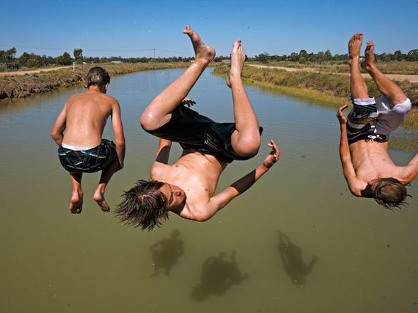 Three Boys in Midair -- Young men jump off a bridge into the Mulwala Canal in Deniliquin, Australia. | Amy Toensing / National Geographic