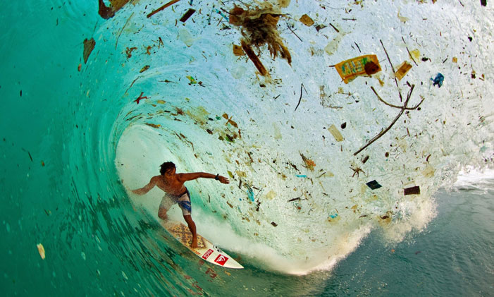 Trash Wave Indonesian surfer Dede Surinaya catches a wave in a remote but garbage-covered bay on Java, Indonesia, the world’s most populated island  "Water and air, the two essential fluids on which all life depends, have become global garbage cans." (Jacques-Yves Cousteau) | Zak Noyle / Population Speak Out